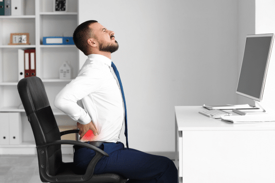 A man suffers back pain while at his desk