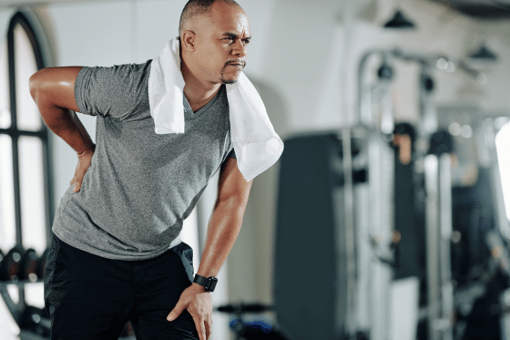 a man suffers back pain at the gym